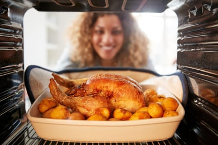 View from inside the oven as a woman cooks Sunday roast chicken dinner